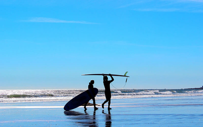 _0002_man-and-womans-silhouette-on-blue-background-beach-with-surf-boards-getting-ready-to-go-surfing_t20_9JVrZY